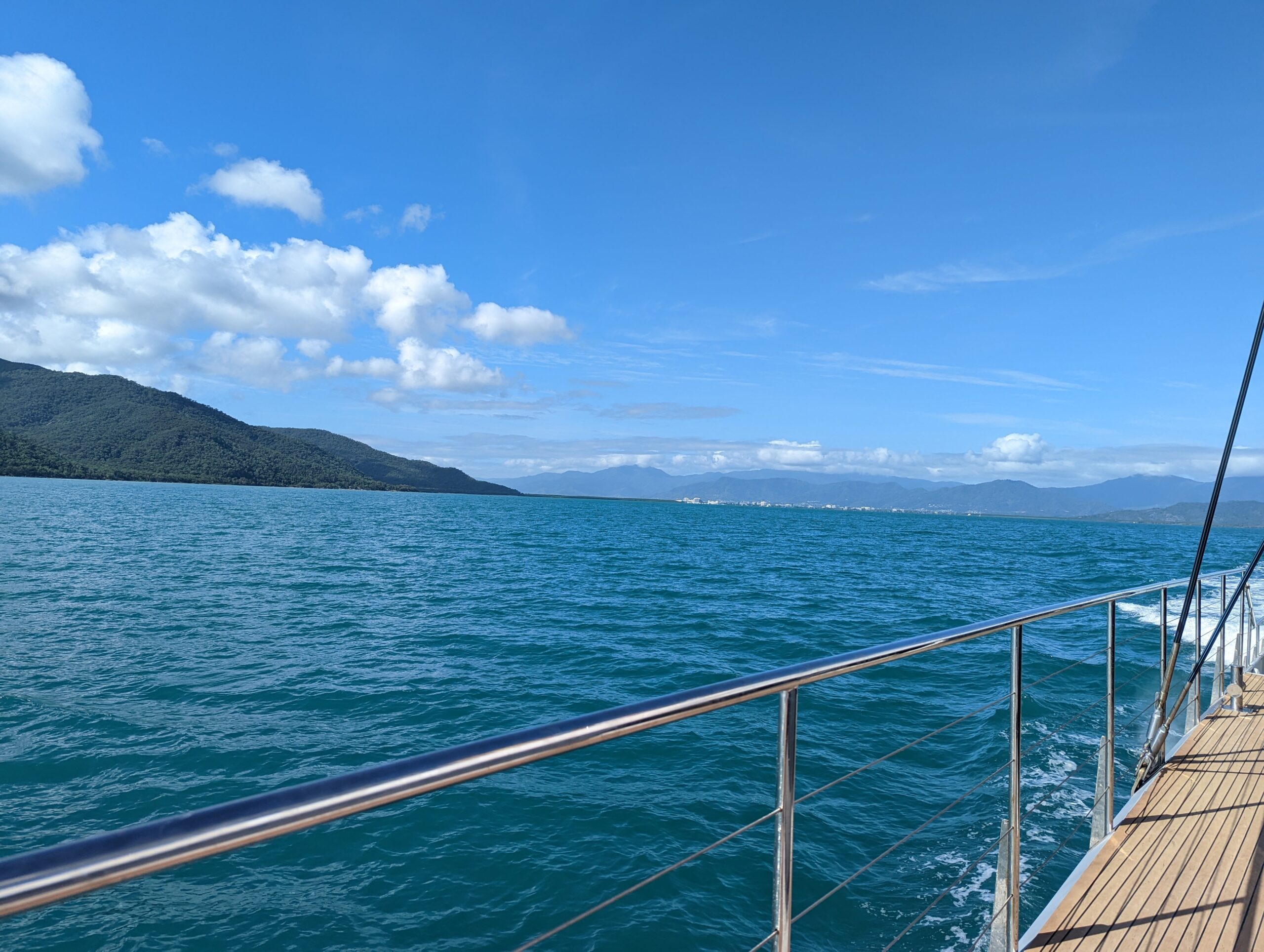 View of Pacific Ocean from boat deck with boat bar. View of land on left horizon