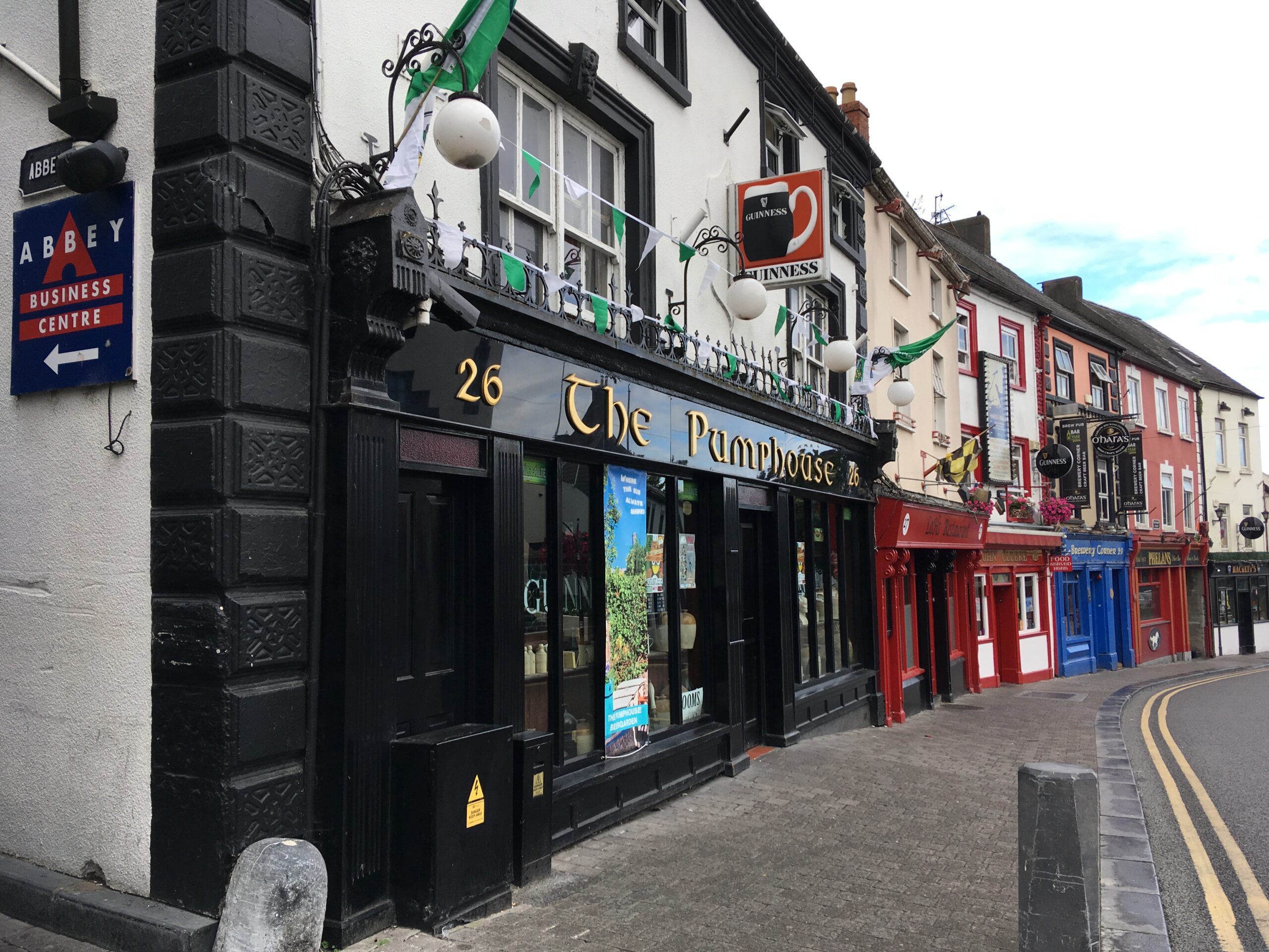 Exterior of pub with black exterior on first level, white facade and black-trimmed windows