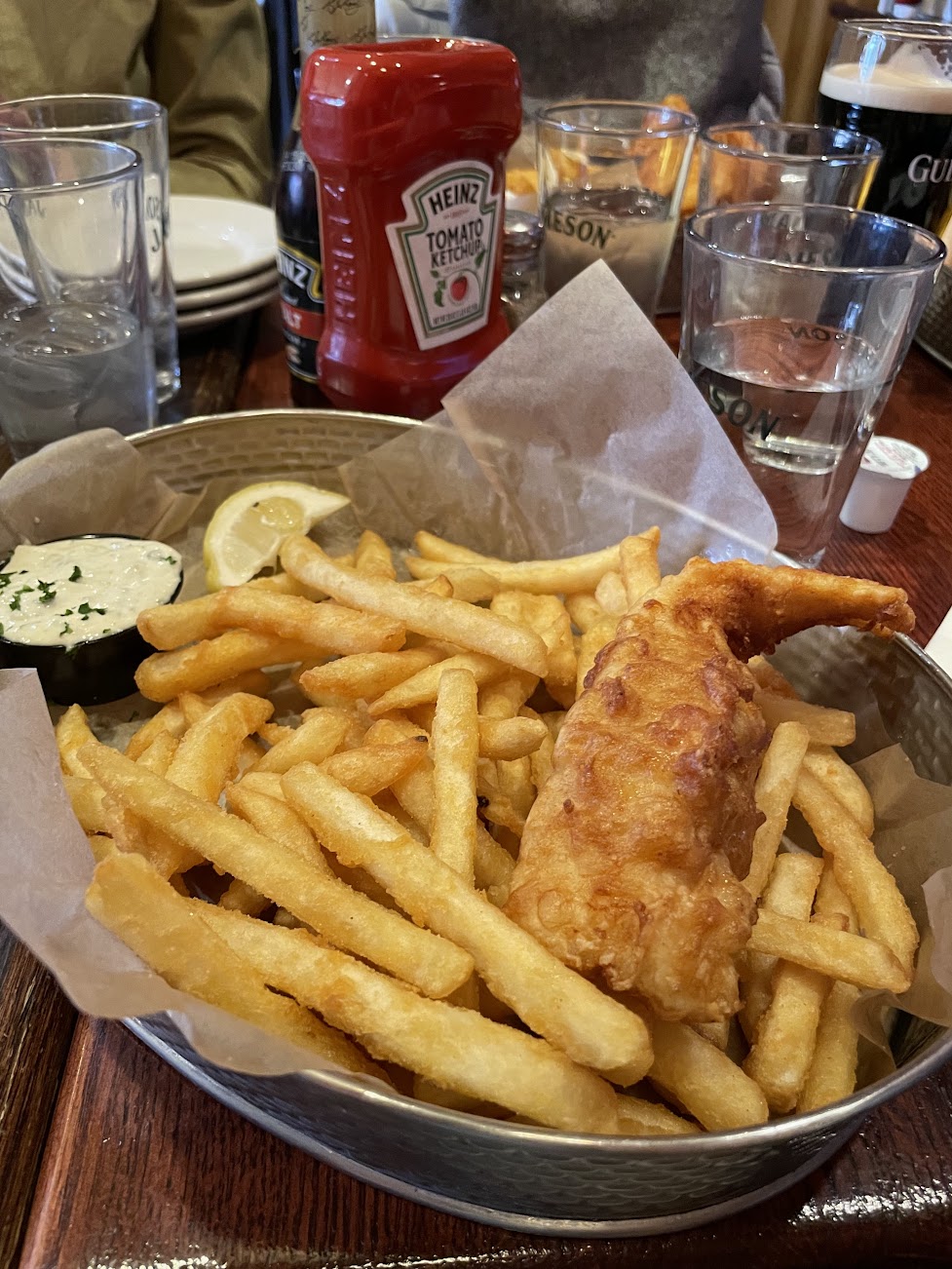 Fish and chips sitting on paper in a tin basket