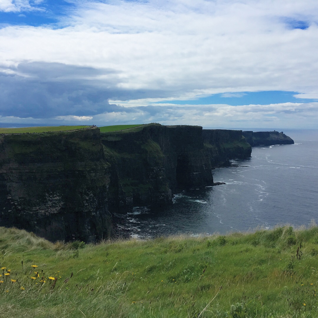 Lines of cliffs along the Atlantic Ocean with a blue and white clouded sky